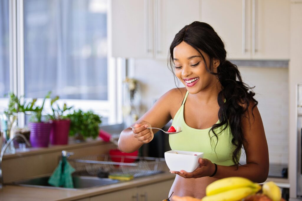 Woman enjoying a nutrient-dense meal with fresh fruit, emphasizing athletic nutrients and a balanced diet for runners to boost recovery.